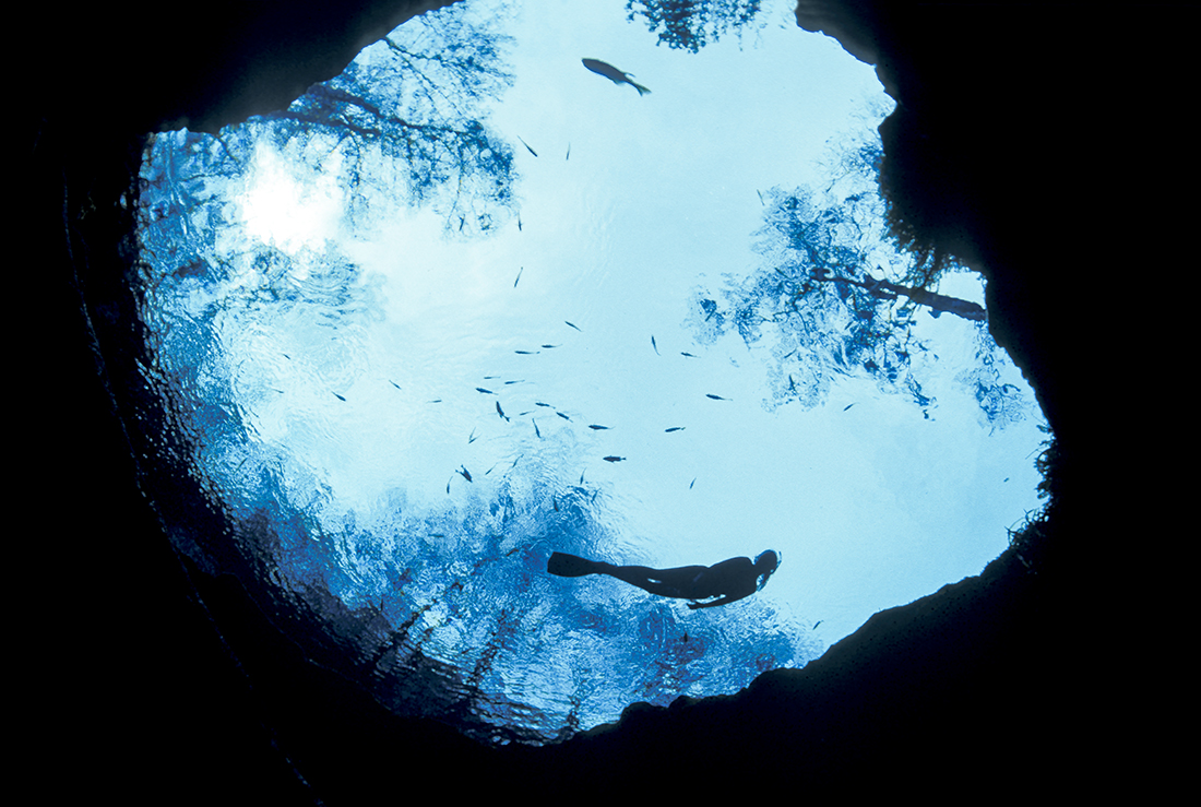 A snorkeler floats effortless overhead of the circular cave entrance of Devil’s Eye at Ginnie Springs.